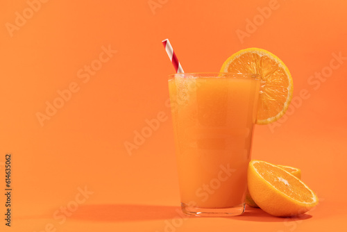 Orange juice with striped non plastic straw isolated on orange. Vegan drink.
