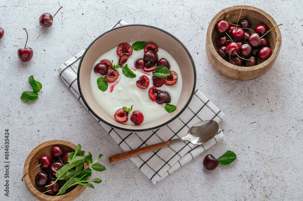 yogurt in a bowl with fresh cherries and mint.