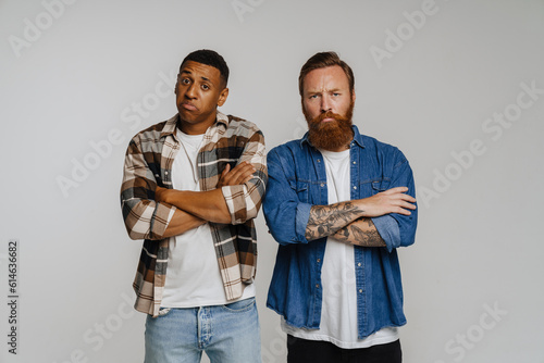 Two upset male friends frowning and posing at camera isolated
