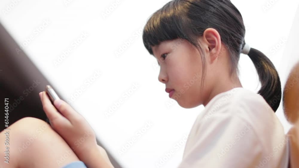 夏の室内でスマホを見ている小学生の女の子の様子