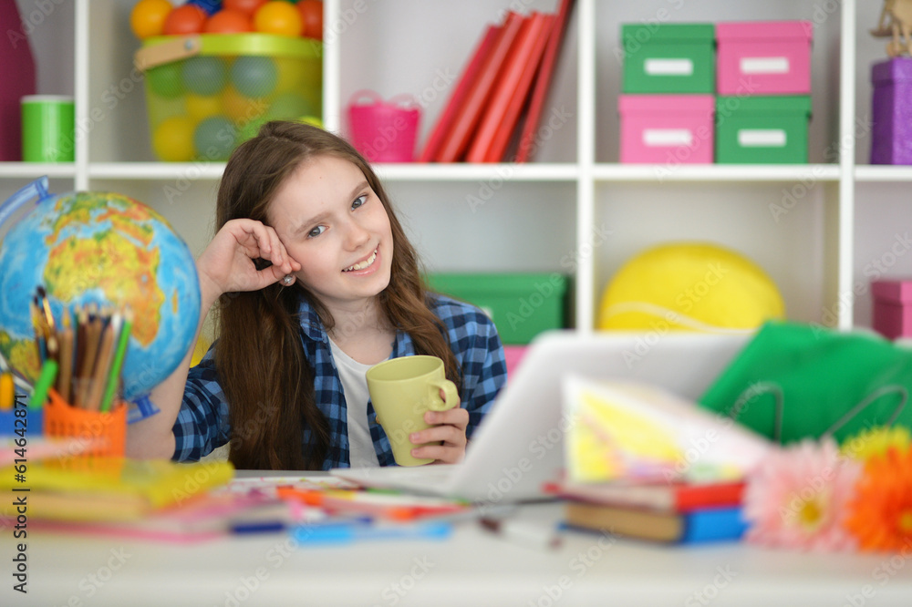 girl with cup using laptop at home at desk girl with cup using laptop at home at desk