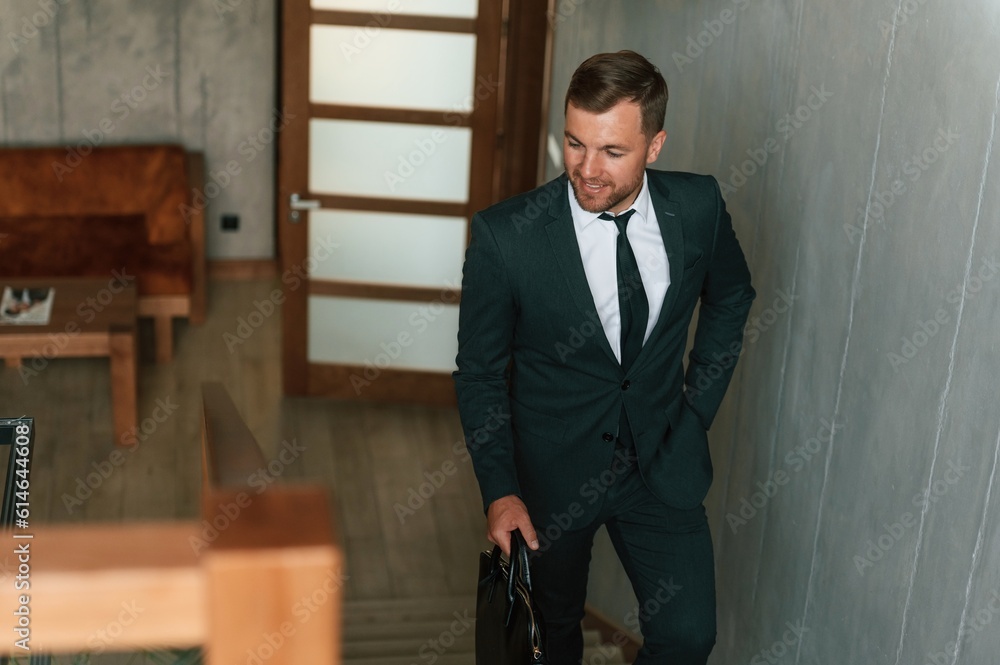 Front view, in the appartment. Handsome businessman is indoors in the hotel room Front view, in the appartment. Handsome businessman is indoors in the hotel room