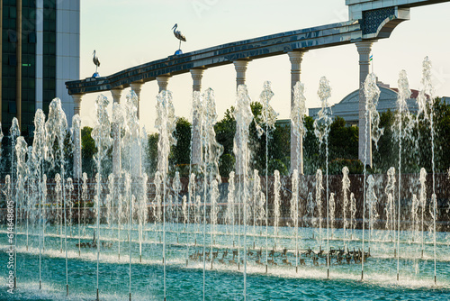 Memorial and rows of fountains illuminated by sunlight at sunset or sunrise in the Independence Square at summertime, Tashkent. photo