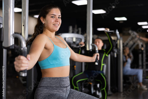 Fit young woman working out at chest fly machine