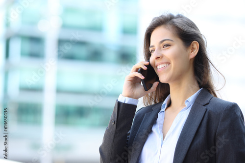 Happy executive talking on phone walking in the street