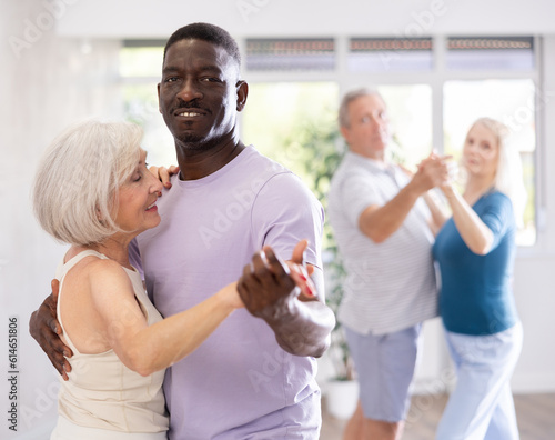 African American man is enjoying his hobby of dancing salsa with his elderly partner at fitness class, relishing in movement and activity. It great way for them to stay active and have fun together. photo