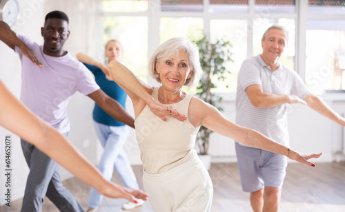 Group of positive adults engaged in sport dances in training room during workout session