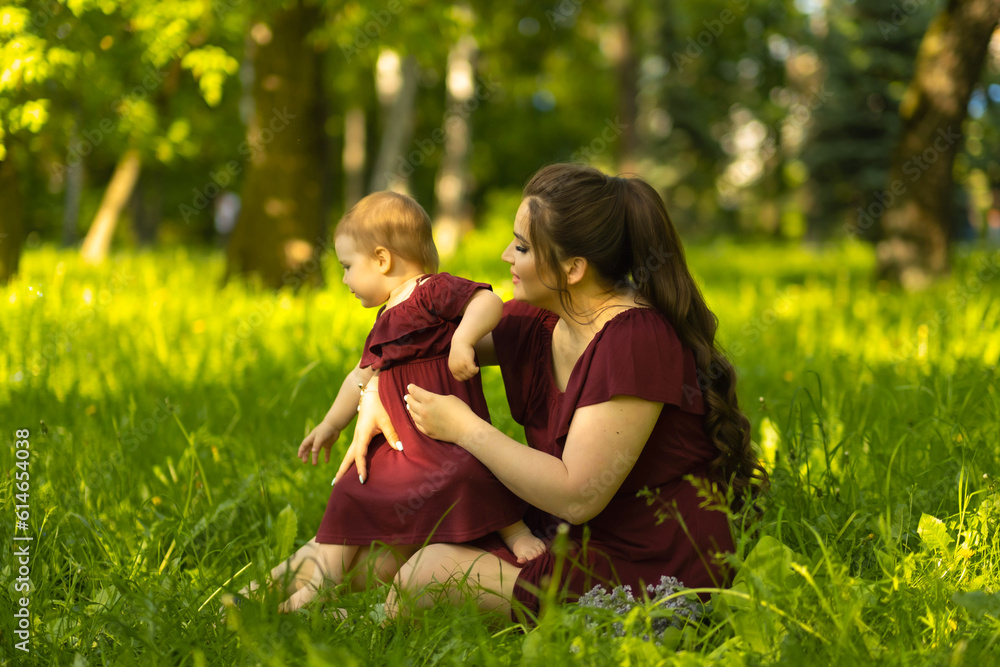 Sun-kissed and joyful: A mother's love shines as brightly as the sun as she shares a moment of joy with her one-year-old daughter in the park. Concept: Happy Motherhood Sun-kissed and joyful: A mother's love shines as brightly as the sun as she shares a moment of joy with her one-year-old daughter in the park. Concept: Happy Motherhood