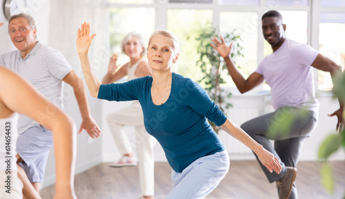 Elderly woman and mature students are engaged in dance class or fitness room with active jazz music. Hobby, healthy lifestyle concept
