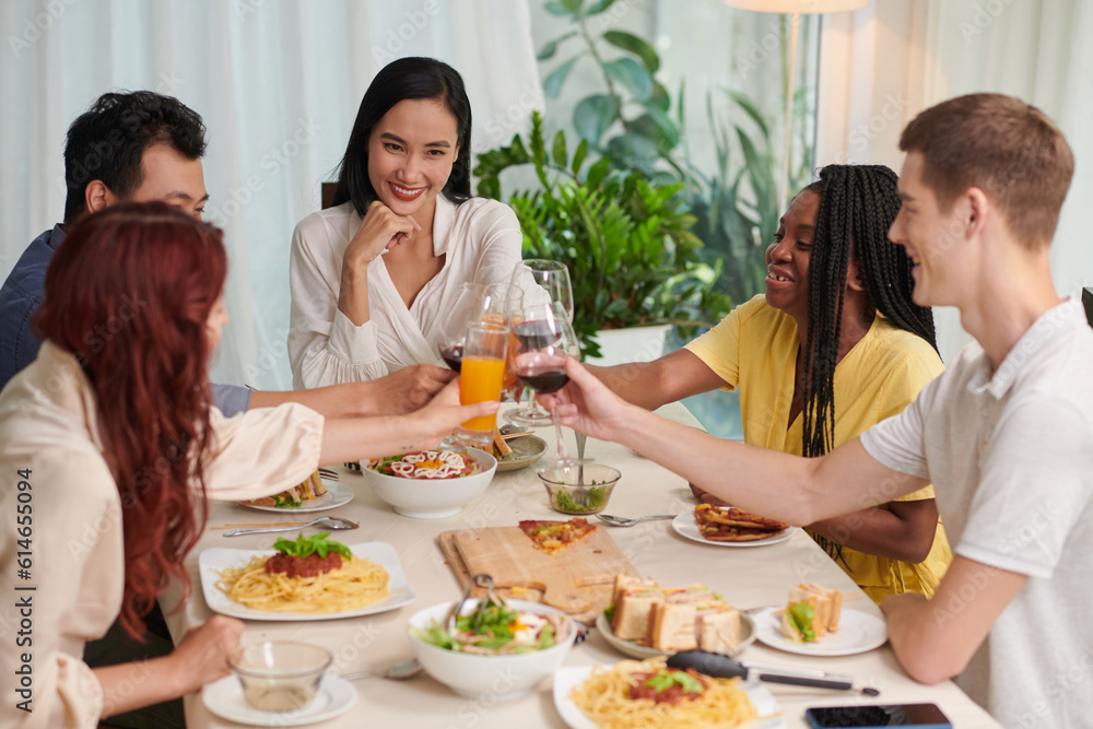 Happy group of friends toasting over dinner table Happy group of friends toasting over dinner table