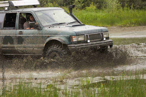 SUV or off-road vehicle crosses a river with splashes of dirty water. Extreme off-road tour in the forest. © Aleksandr