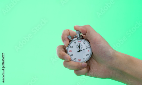 People hand holding stopwatch on green background