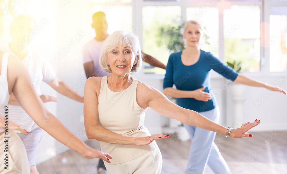 Group of positive adults engaged in sport dances in training room during workout session
