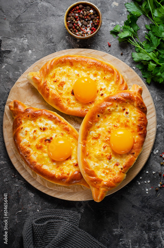 Ajarian Khachapuri, filled with cheese and topped with egg yolk, traditional Georgian Khachapuri on Dark Background