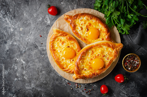 Ajarian Khachapuri, filled with cheese and topped with egg yolk, traditional Georgian Khachapuri on Dark Background