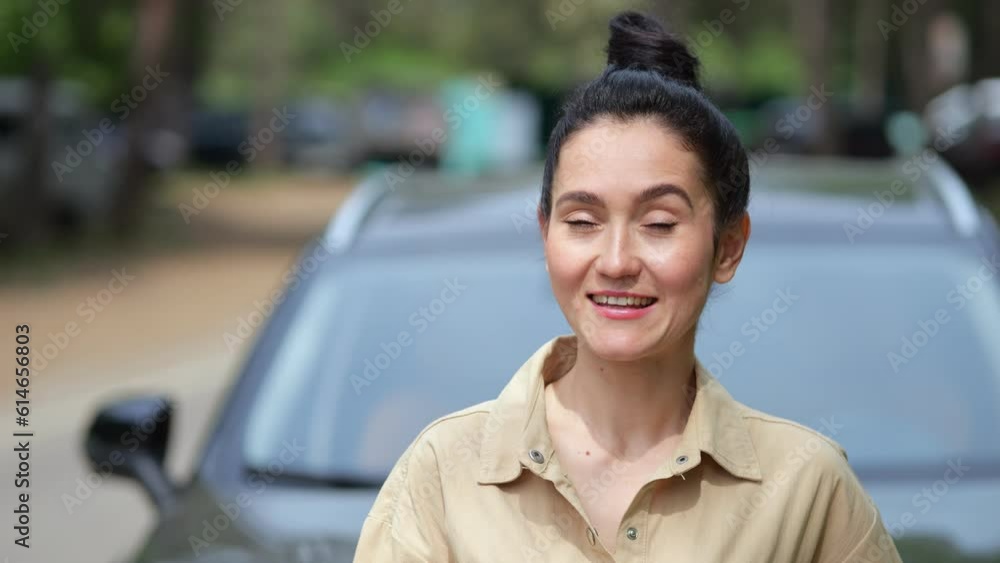 Brunette businesswoman stands with smiling expression next to modern car. Woman enjoying purchase of new vehicle in luxury car dealership Brunette businesswoman stands with smiling expression next to modern car. Woman enjoying purchase of new vehicle in luxury car dealership