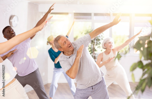 Enthusiastic elderly gentleman immersing in world of contemporary dance with diverse group of adults, performing dabbing move