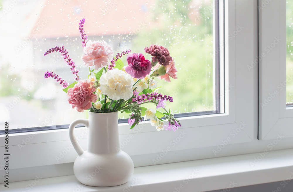 pink and purple summer flowers in white jug on windowsill pink and purple summer flowers in white jug on windowsill