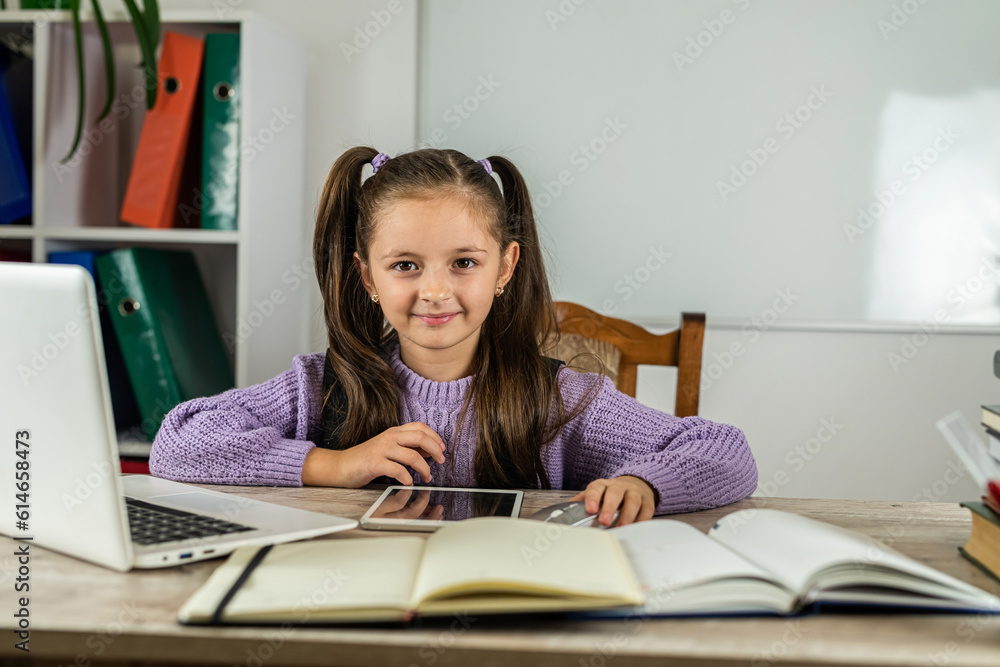 smiling little girl is watching a video lesson on the computer. smiling little girl is watching a video lesson on the computer.
