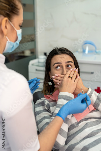 Photography Young female patient covering her mouth with hands at the dentist's appointment