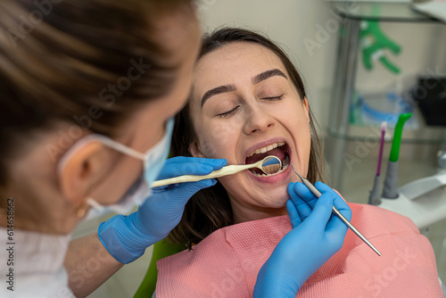Caucasian young woman sitting at clinic receiving treatment from dentist doctor