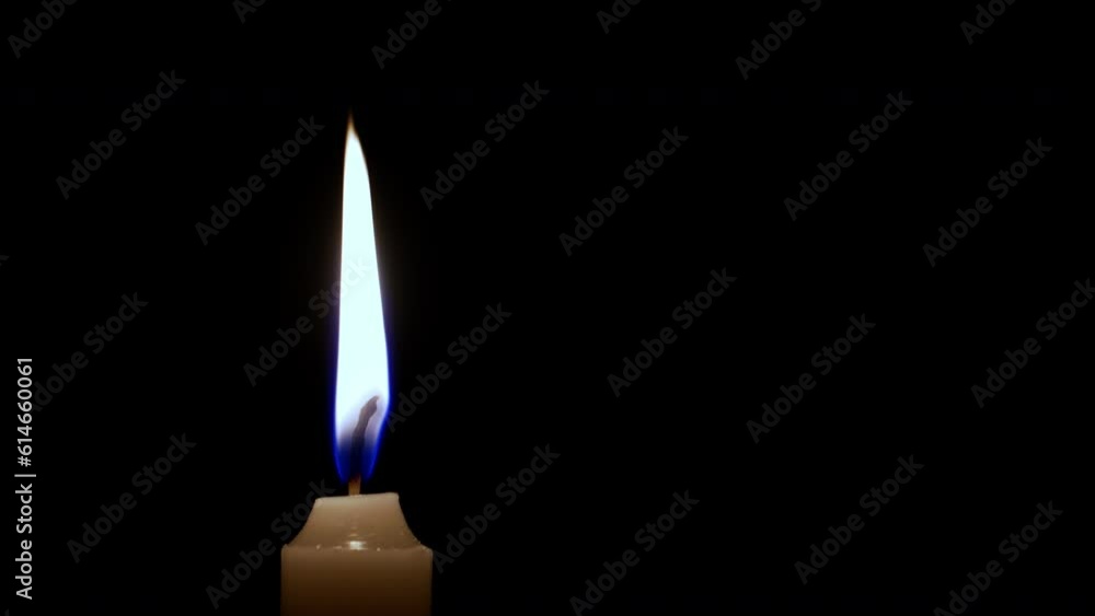 The camera pulls back from a brightly burning candle against a black background. 4K footage of a ceremonial candle. A symbol of death, memory and repose. The camera pulls back from a brightly burning candle against a black background. 4K footage of a ceremonial candle. A symbol of death, memory and repose.