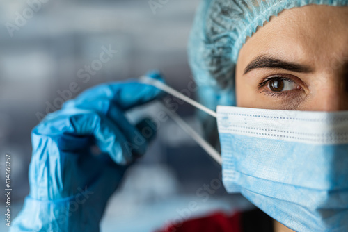 Fototapet Portrait of tired young doctor taking off medical face mask after a shift in cli