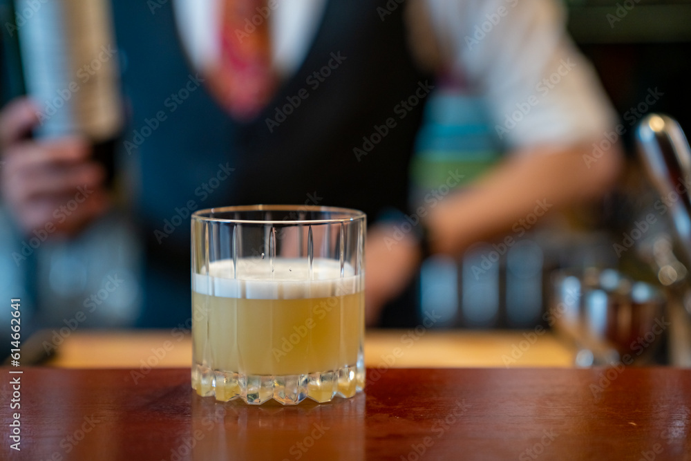 Professional male bartender preparing and serving cocktail drink to customer on bar counter at luxury nightclub. Barman making mixed alcoholic drink for celebrating holiday party at restaurant bar.