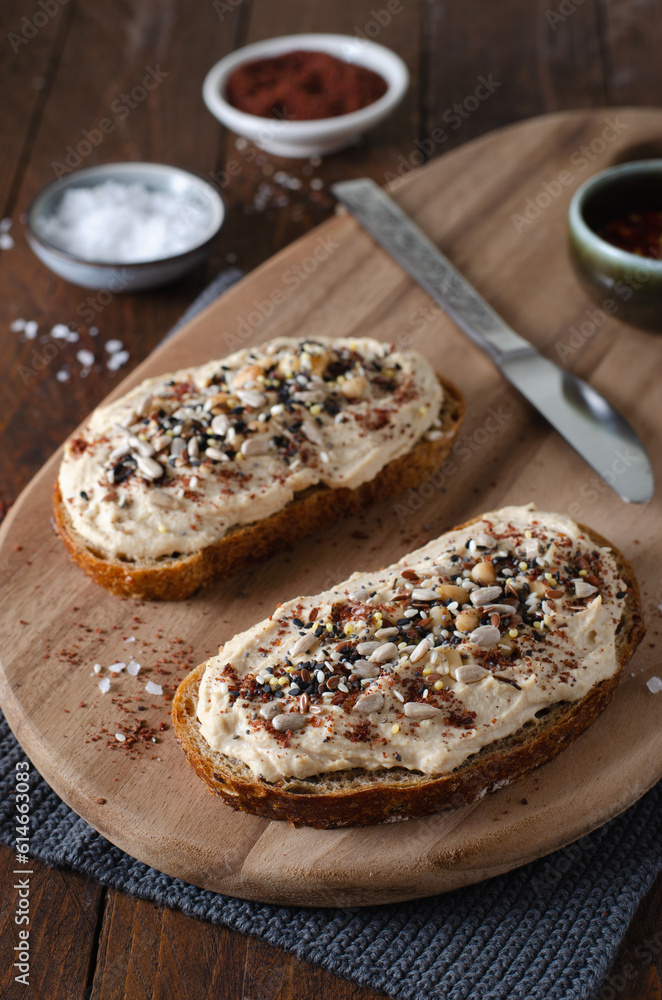 Hummus Toast with Rustic Bread, Vegetarian Snack or Breakfast on Wooden Background Hummus Toast with Rustic Bread, Vegetarian Snack or Breakfast on Wooden Background