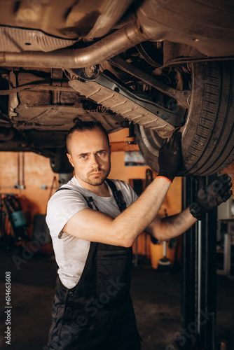 Portrait of a mechanic repairing a lifted car