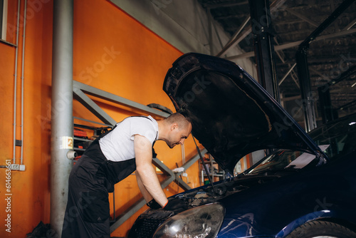 Portrait of mechanic checking parts of automobile © Roman