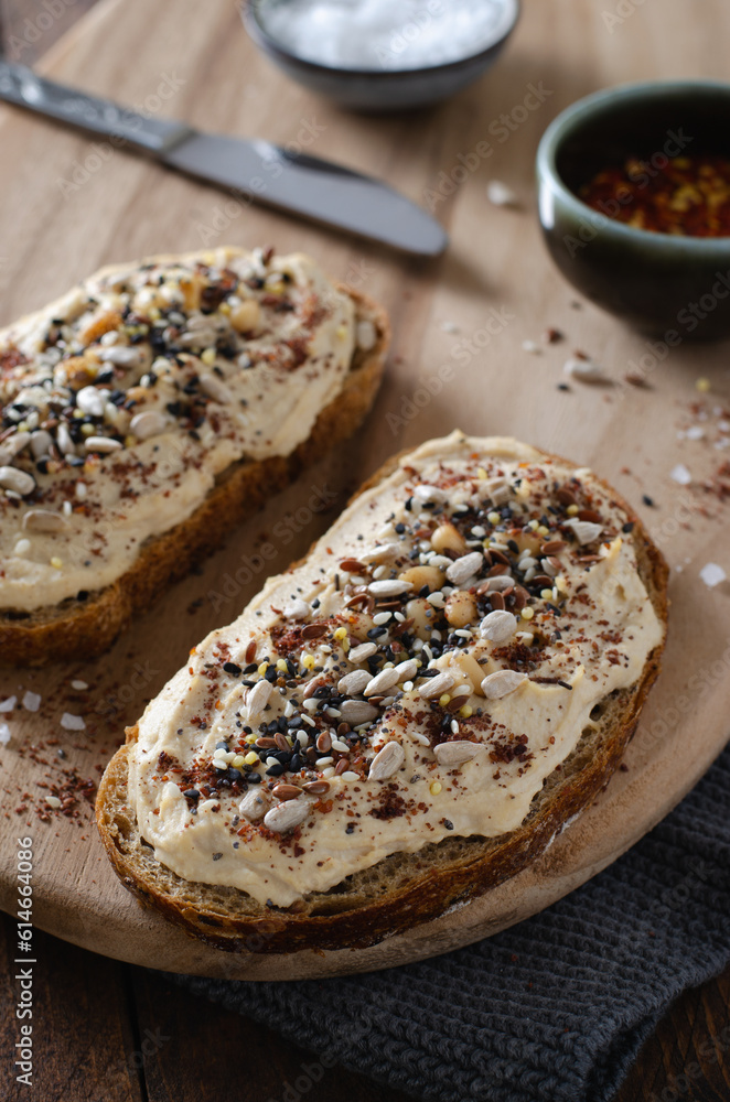 Hummus Toast with Rustic Bread, Vegetarian Snack or Breakfast on Wooden Background Hummus Toast with Rustic Bread, Vegetarian Snack or Breakfast on Wooden Background