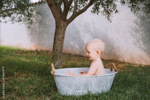 Baby boy taking bath in tub at backyard photo