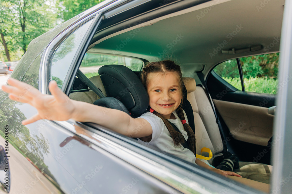 Happy girl waving hand sitting in car Happy girl waving hand sitting in car