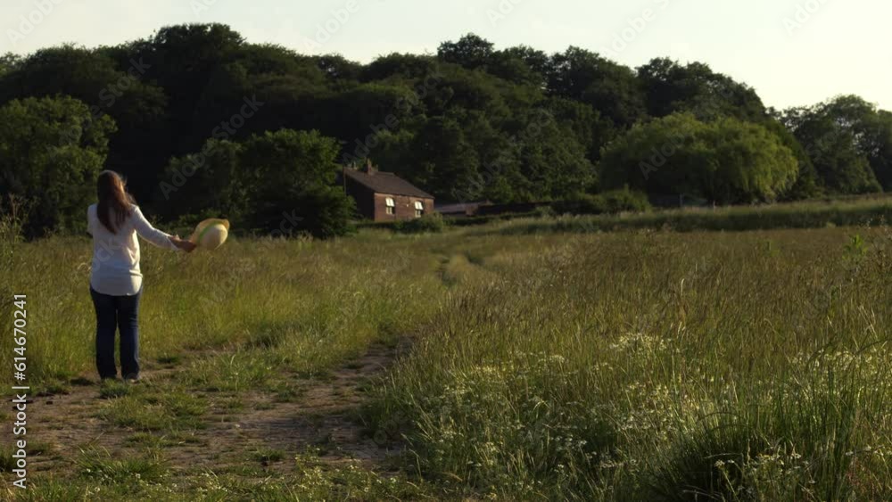 Woman walking home through farmland meadow Woman walking home through farmland meadow