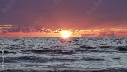 Orange sunset at the baltic sea in Latvia with waves in the foreground