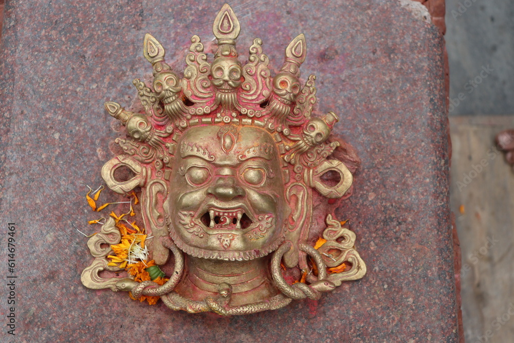 Devil's face mask made up of golden metal with sharp teeth and smiling face. Hindu Tibetan deity of Mahakal-  god of death.