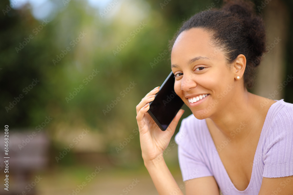 Happy black woman calling on phone looking at you Happy black woman calling on phone looking at you