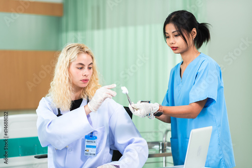 Caucasian woman dermatologist doctor examining asian young adult patient in clinic. Skin care and beauty clinic business industry