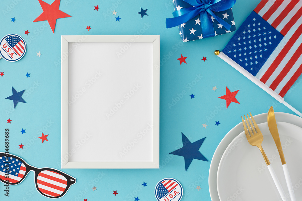 Obraz premium Idea for patriotic festivities on July 4th. Top view flat lay of plates, cutlery, gift box, american flag, paper props, stars on light blue background with blank frame for advert or text