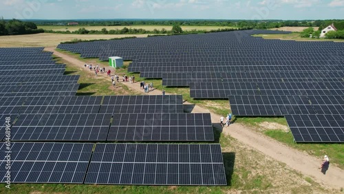 Groupe de gens marchand au milieu de champ de panneau solaire