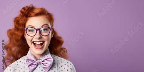Happy ginger girl with big eyeglasses and bow ties. Isolated on solid purple background photo