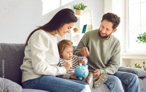 Foto Happy young family saving money in piggy bank