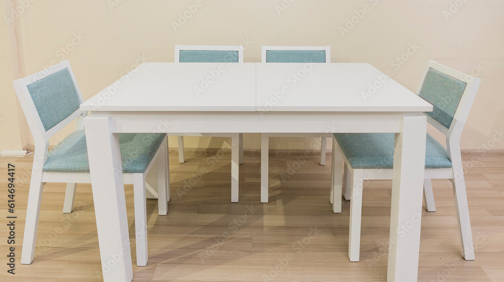 A white table with four legs and four chairs stands in the room A white table with four legs and four chairs stands in the room