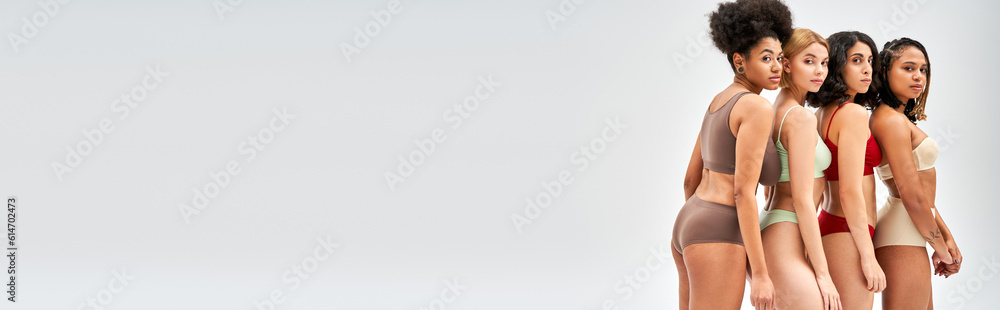 Multiethnic women in colorful and stylish lingerie standing next to each other and looking at camera isolated on grey, different body types and self-acceptance concept, multicultural models, banner Multiethnic women in colorful and stylish lingerie standing next to each other and looking at camera isolated on grey, different body types and self-acceptance concept, multicultural models, banner