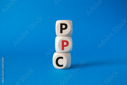 PPC - Pay Per Click symbol. Wooden cubes with words PPC. Beautiful blue background. Business and PPC concept. Copy space.