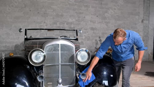 German retro car, man wiping dust from car in garage. A collection of old cars from World War II
