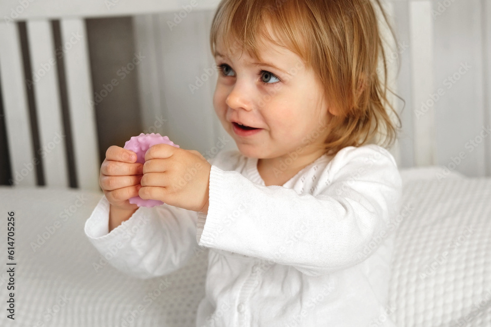 Cute baby girl playing tactile knobby balls. Young child hand plays sensory massage ball. Enhance the cognitive, physical process. Brain development. Support for Children with ADHD, autism, fidgeting Cute baby girl playing tactile knobby balls. Young child hand plays sensory massage ball. Enhance the cognitive, physical process. Brain development. Support for Children with ADHD, autism, fidgeting