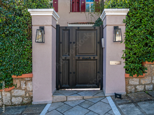 A luxury house entrance dark charcoal painted iron door by the sidewalk. Travel to Athens, Greece.