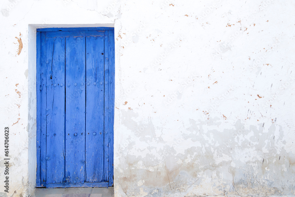 White wall with a blue wooden door White wall with a blue wooden door